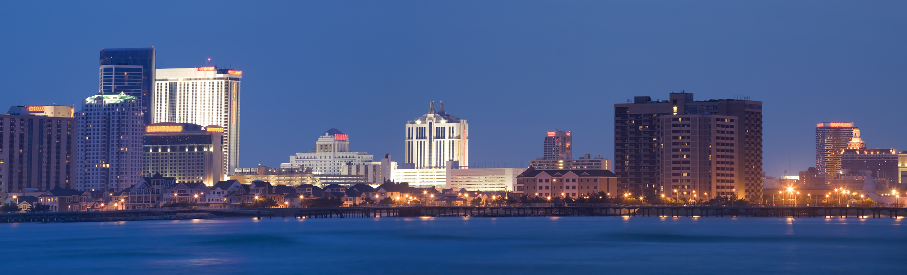 "Panorama of the cityscape of Atlantic City,NJ in evening light. 2 image merge. Soft water of the inlet due to slow shutter.Lighted casino names and logos are blurred but not removed."